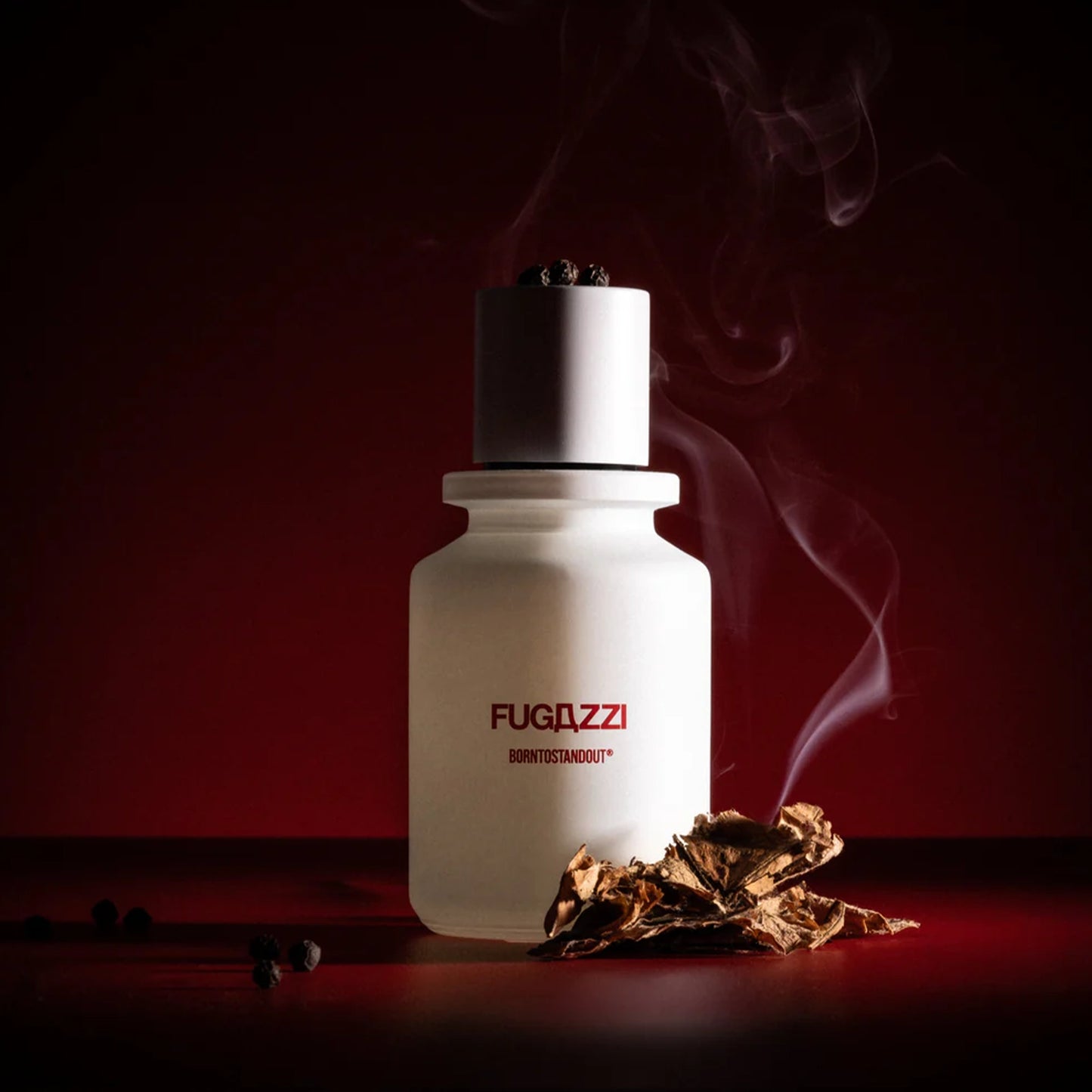 Fugazzi Born to Stand Out perfume bottle with smoke and tobacco leaves on dark red background