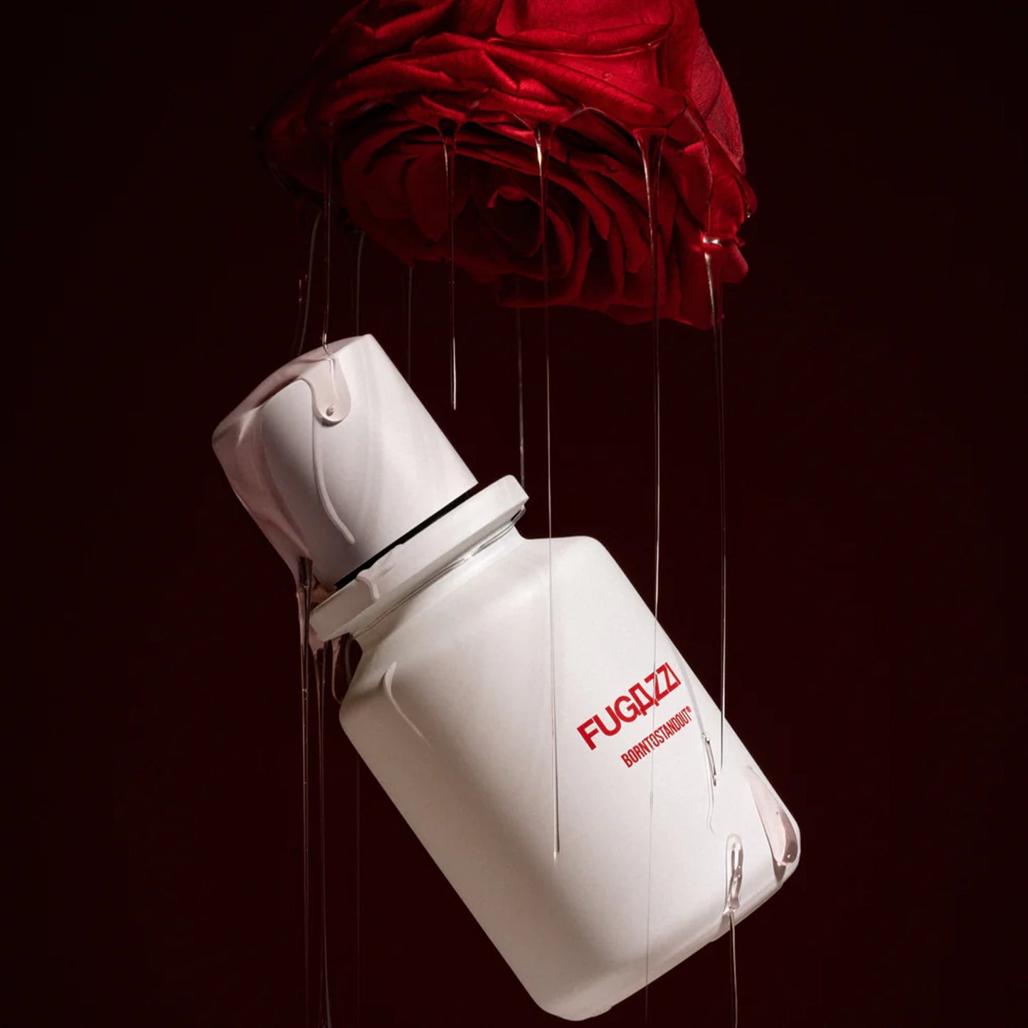 Born to Stand Out by Fugazzi perfume bottle with dripping red rose on dark background